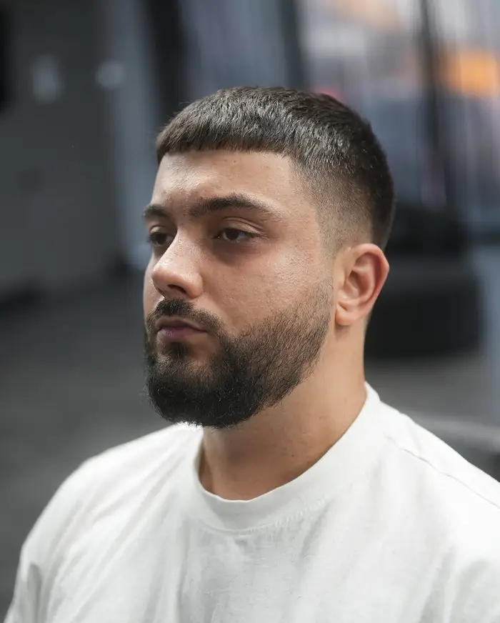 French crop with a mid fade and a full beard on coarse dark hair at ONYX barbershop in Hallandale Beach, FL