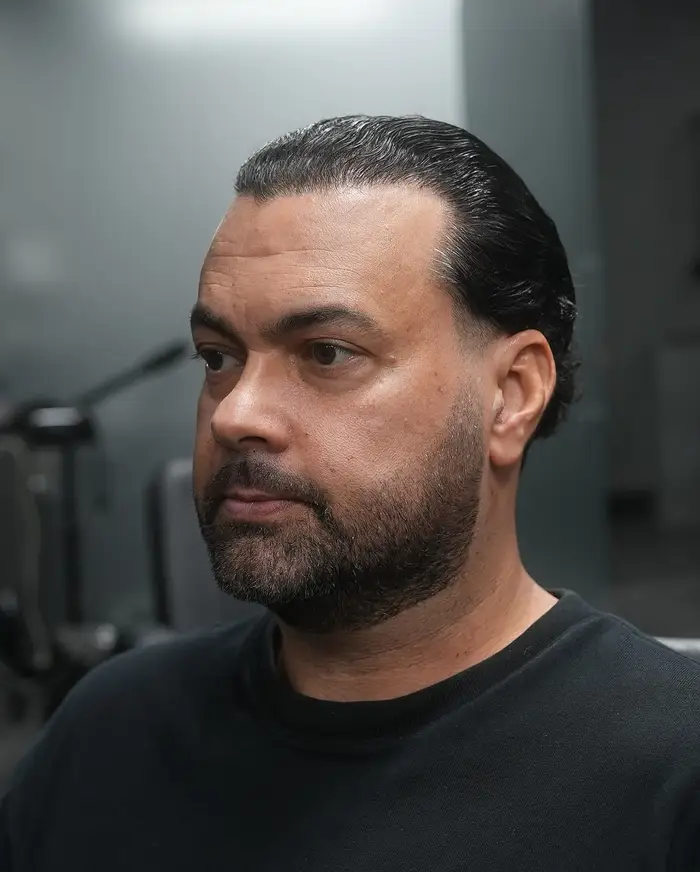 Slicked-back cut with a taper and a full beard on greying hair at ONYX barbershop in Hallandale Beach, FL